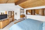 This stunning bedroom boasts a unique architectural design with a wooden sloped ceiling and a cozy ambiance.