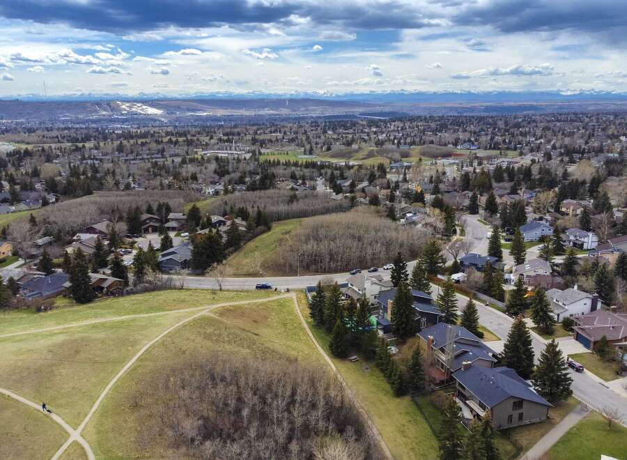 An aerial view showcases a beautiful residential area with lush greenery and stunning mountain views.