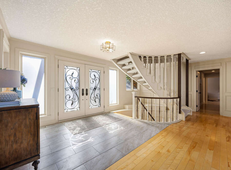 Step into luxury with this stunning entryway, featuring a grand staircase and elegant double doors.