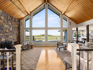 This stunning property boasts a grand living space with soaring ceilings and expansive windows that flood the room with natural light.