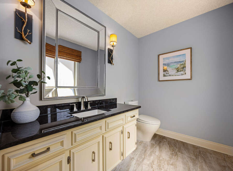This elegant bathroom features a stylish vanity with a sleek black countertop and cream-colored cabinets, offering ample storage.