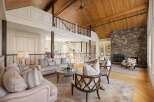 This stunning living room boasts a grand, open design with a soaring wood-paneled ceiling and a cozy stone fireplace.