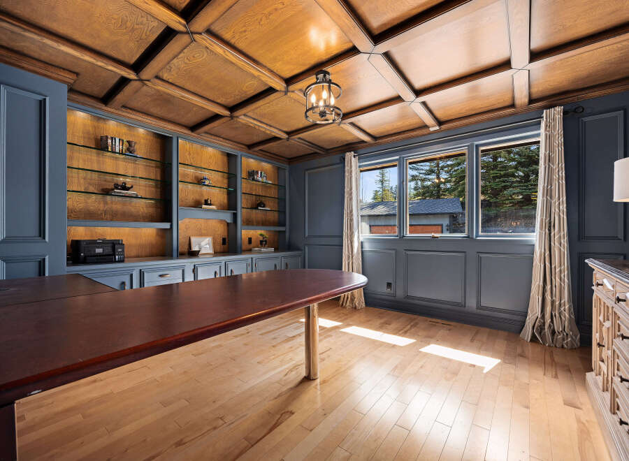 Step into luxury with this stunning home office, featuring a rich wood ceiling and built-in shelving.