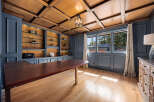 Step into luxury with this stunning home office, featuring a rich wood ceiling and built-in shelving.