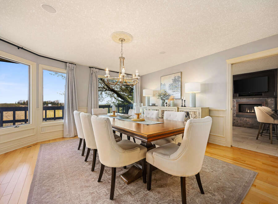 This elegant dining room boasts a stunning chandelier, a large wooden dining table, and comfortable seating for a gathering.