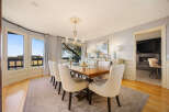 This elegant dining room boasts a stunning chandelier, a large wooden dining table, and comfortable seating for a gathering.
