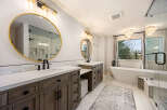Step into luxury with this stunning bathroom! Featuring a sleek design, this space boasts a double vanity with ample storage and a beautiful round mirror.