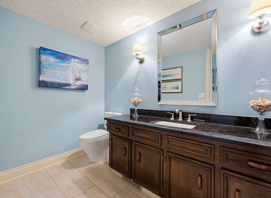 This stunning bathroom features a beautiful vanity with dark wood cabinets and a sleek black countertop.