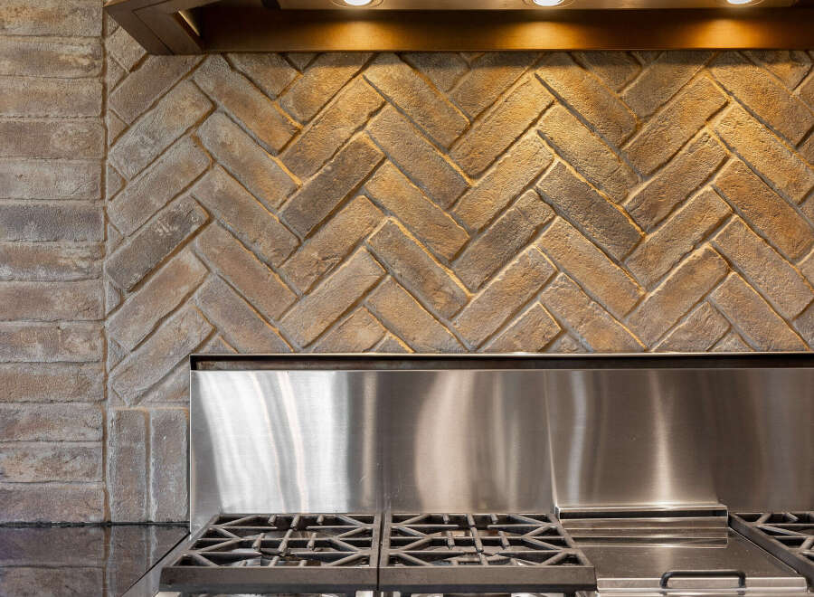 This stunning kitchen boasts a modern stainless steel range and a beautiful brick backsplash, creating a warm and inviting atmosphere.