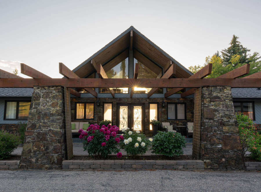 This stunning property boasts a unique architectural design, featuring a striking wooden pergola and a stone facade.