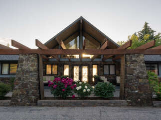 This stunning property boasts a unique architectural design, featuring a striking wooden pergola and a stone facade.
