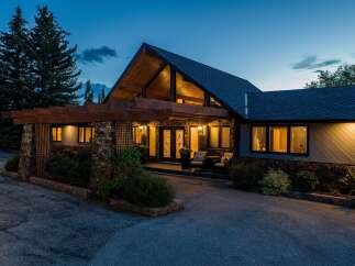 This stunning property boasts a unique architectural design with a striking A-frame roof and inviting entrance.