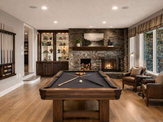 Experience ultimate relaxation and entertainment in this stunning basement game room, featuring a professional billiard table and a cozy stone fireplace.