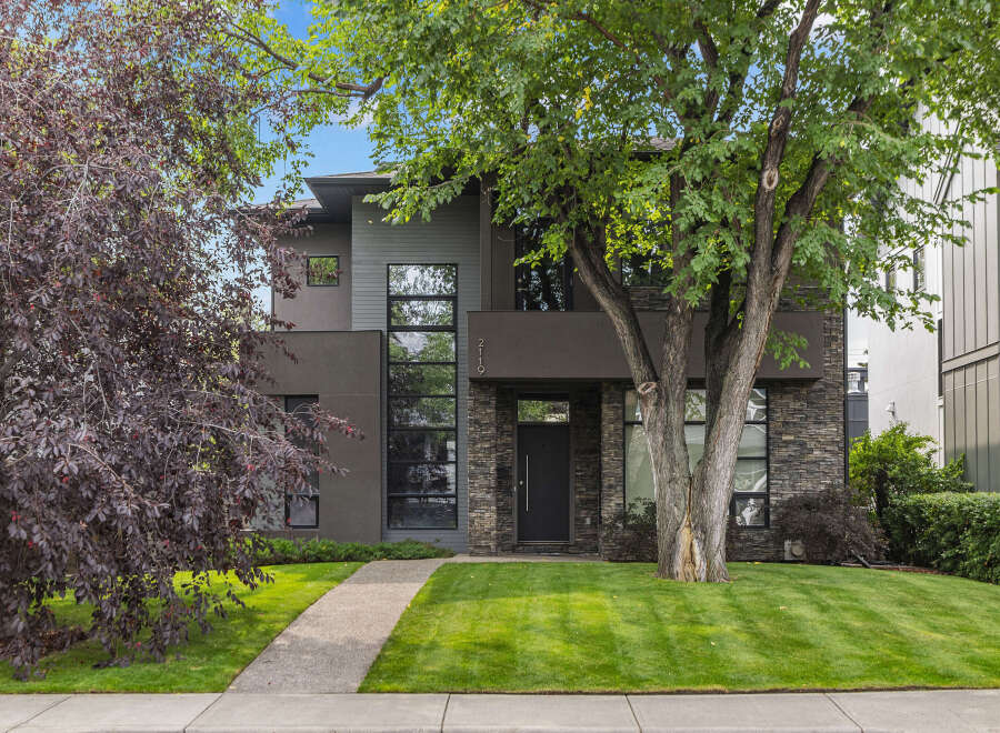 This stunning modern home boasts a sleek exterior with a combination of stone and dark siding.