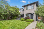 This stunning modern home boasts a beautifully manicured lawn and lush landscaping, creating an inviting outdoor space.