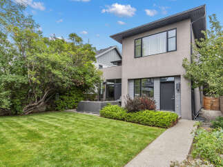 This stunning modern home boasts a beautifully manicured lawn and lush landscaping, creating an inviting outdoor space.