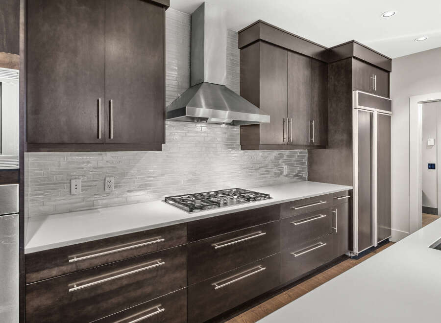 This modern kitchen boasts sleek dark wood cabinetry, offering ample storage and a sophisticated aesthetic.