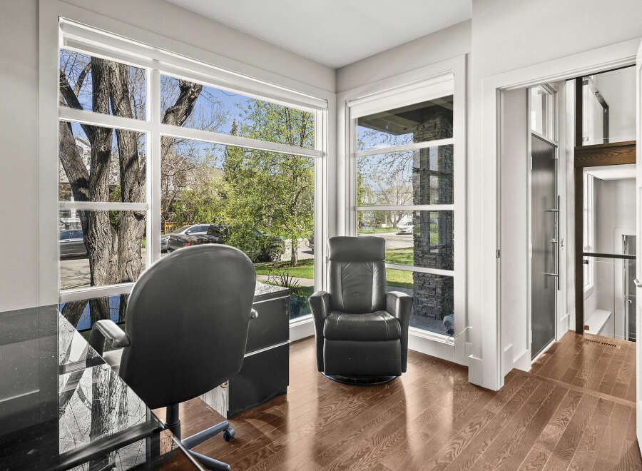 This stunning home office boasts an abundance of natural light, thanks to the expansive windows that frame the lush outdoor scenery.