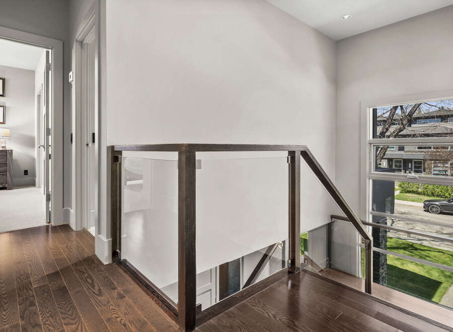This stunning property boasts a modern interior with a sleek staircase featuring glass panels and dark wood accents.