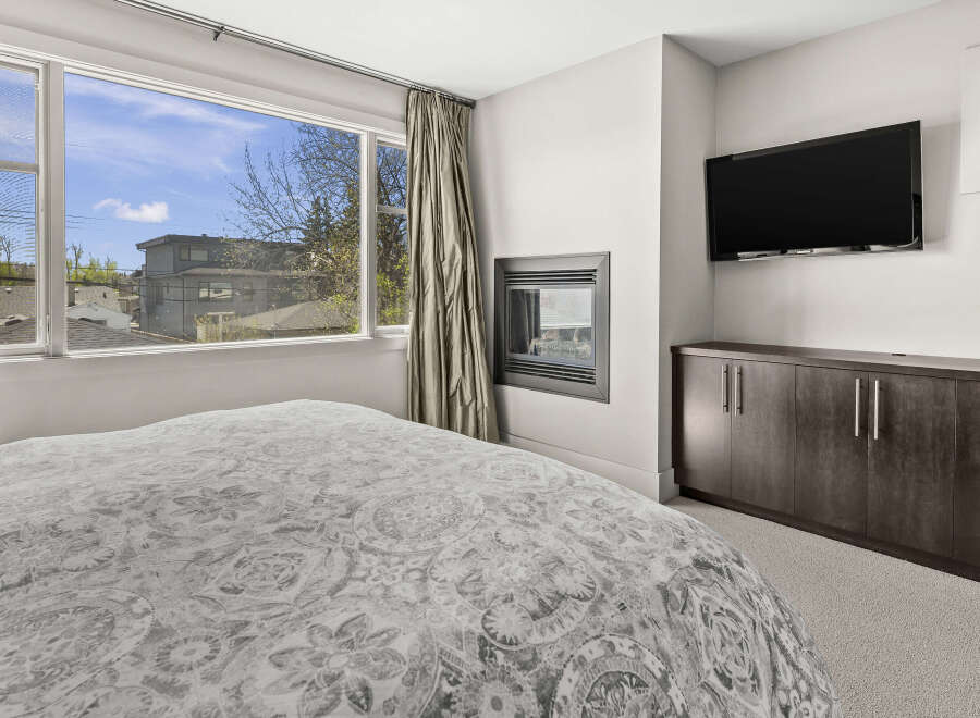This stunning bedroom features a modern fireplace and a large flat-screen TV, perfect for cozy nights in.