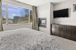 This stunning bedroom features a modern fireplace and a large flat-screen TV, perfect for cozy nights in.
