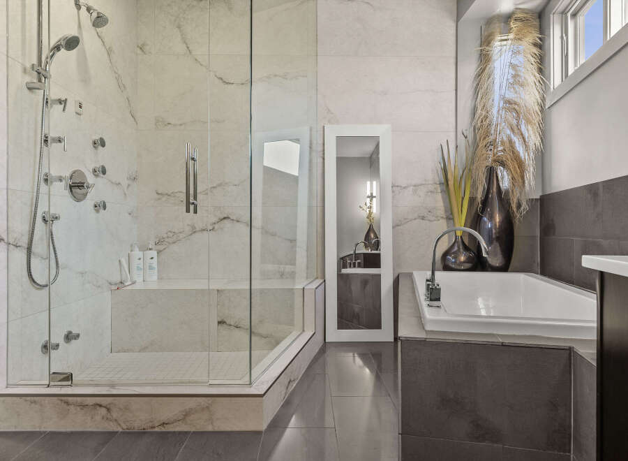 Step into luxury with this stunning bathroom featuring a spacious walk-in shower with multiple shower heads and a relaxing soaking tub.