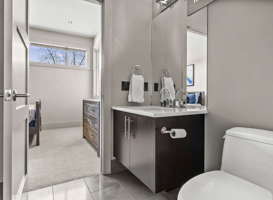This modern bathroom features a sleek vanity with a dark wood finish, complemented by a pristine white countertop.