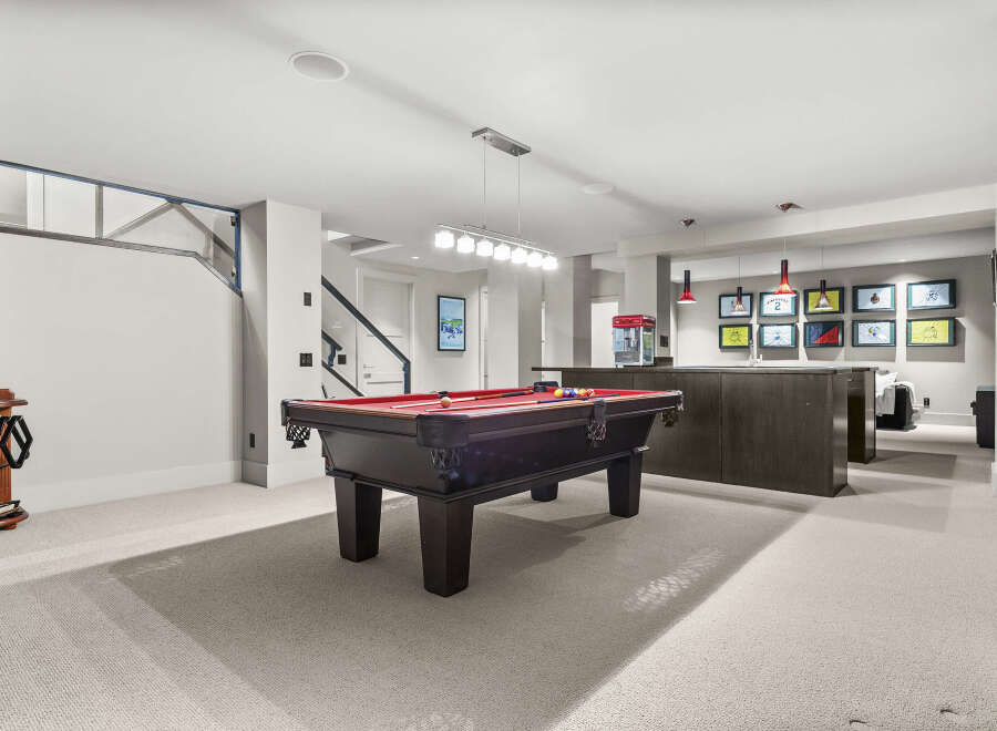 This stunning basement recreation room features a pool table, perfect for entertaining guests.