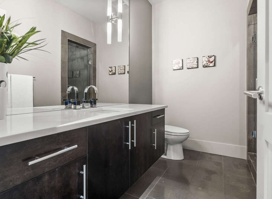 This modern bathroom boasts a sleek design with dark wood cabinetry and a pristine white countertop.
