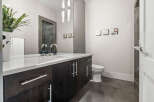 This modern bathroom boasts a sleek design with dark wood cabinetry and a pristine white countertop.