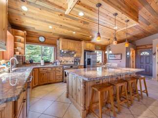 This stunning kitchen boasts a rustic charm with its wooden cabinetry, countertops, and ceiling, creating a warm and inviting atmosphere.