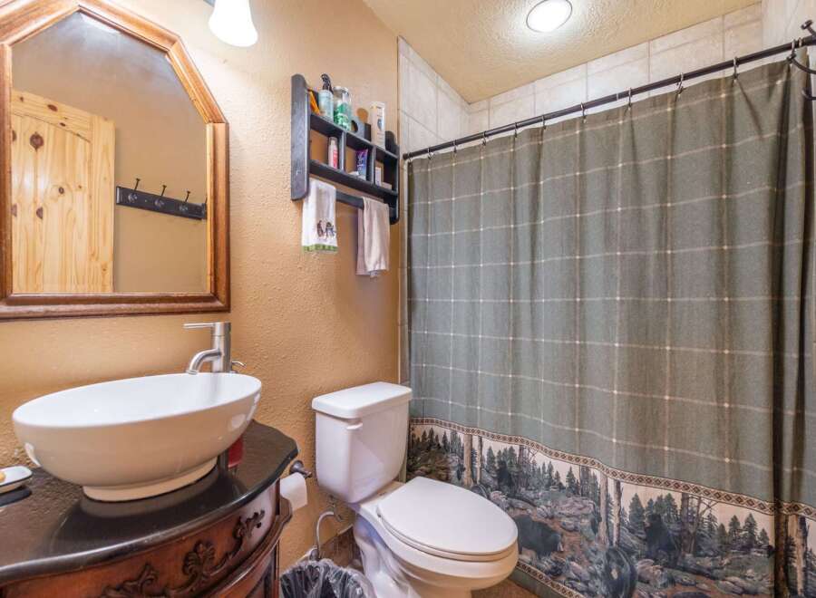 Step into this charming bathroom, featuring a stylish vessel sink atop a dark vanity.