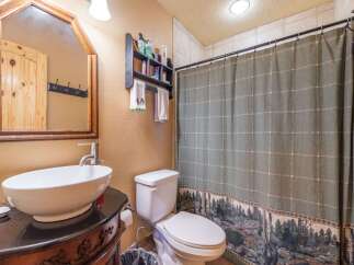 Step into this charming bathroom, featuring a stylish vessel sink atop a dark vanity.