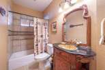 Step into this charming bathroom, featuring a rustic vanity with a unique gold sink and a stylish black countertop.