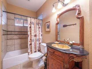 Step into this charming bathroom, featuring a rustic vanity with a unique gold sink and a stylish black countertop.