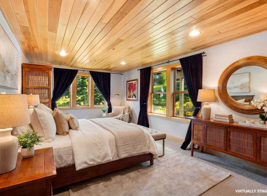 Step into luxury in this stunning bedroom featuring a warm wooden ceiling and elegant dark curtains.