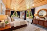 Step into luxury in this stunning bedroom featuring a warm wooden ceiling and elegant dark curtains.