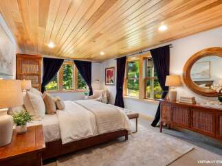 Step into luxury in this stunning bedroom featuring a warm wooden ceiling and elegant dark curtains.