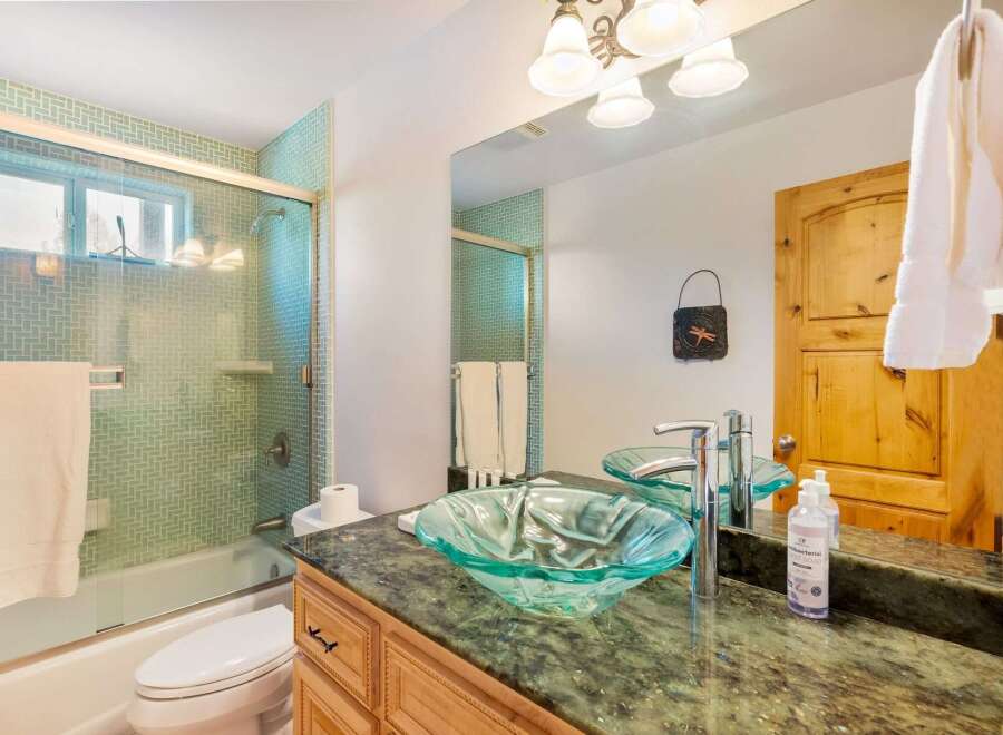 Step into a beautifully designed bathroom featuring a stylish glass vessel sink and a luxurious green granite countertop.