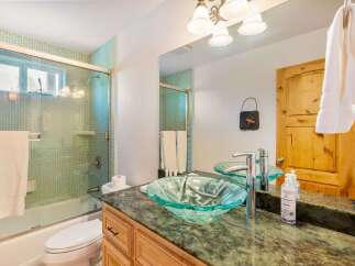 Step into a beautifully designed bathroom featuring a stylish glass vessel sink and a luxurious green granite countertop.