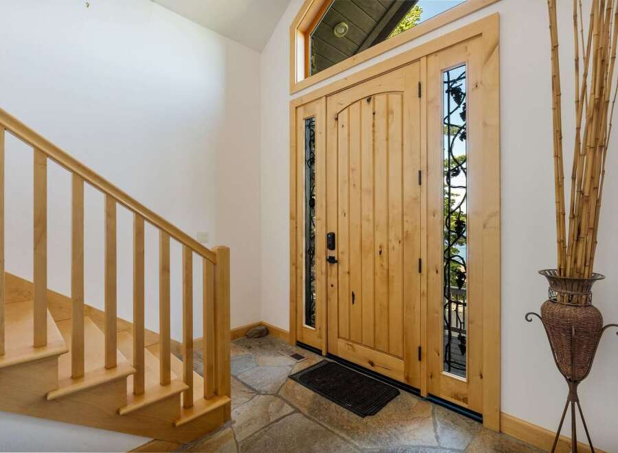 Step into luxury with this stunning entryway! Featuring a beautiful wooden door with intricate glass detailing, this space exudes warmth and elegance.