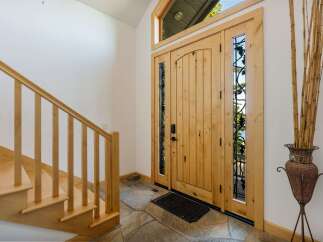 Step into luxury with this stunning entryway! Featuring a beautiful wooden door with intricate glass detailing, this space exudes warmth and elegance.