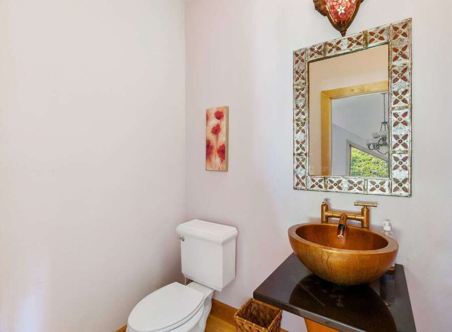 This stunning bathroom features a unique gold-toned sink and a stylish mirror, creating a luxurious and inviting space.