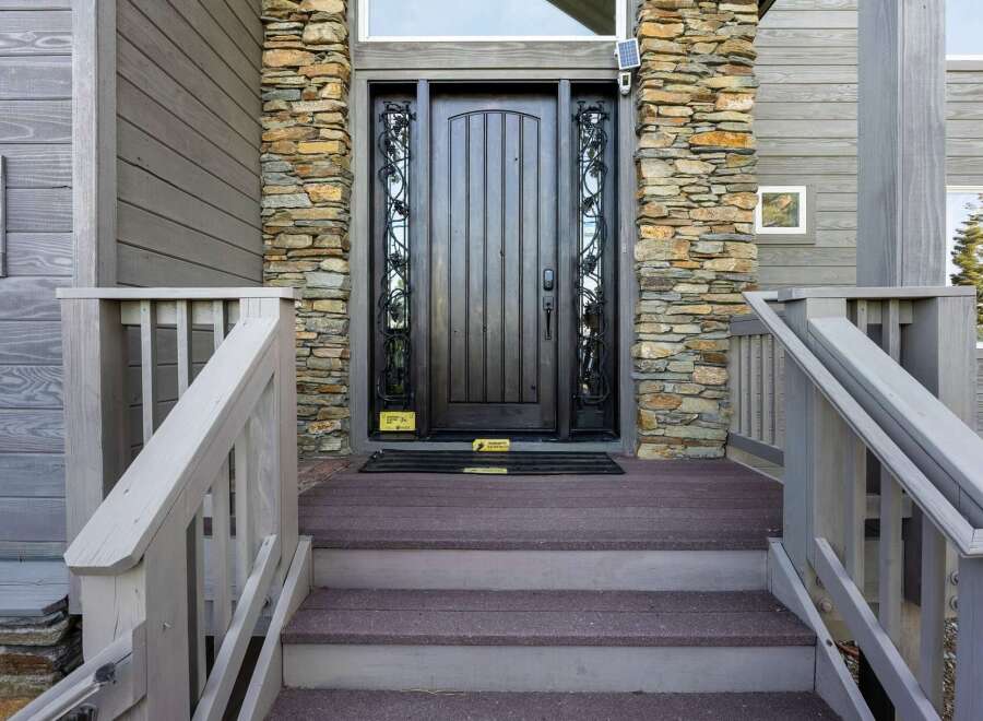 This stunning property boasts a beautifully crafted entrance, featuring a dark wooden door complemented by stone accents.