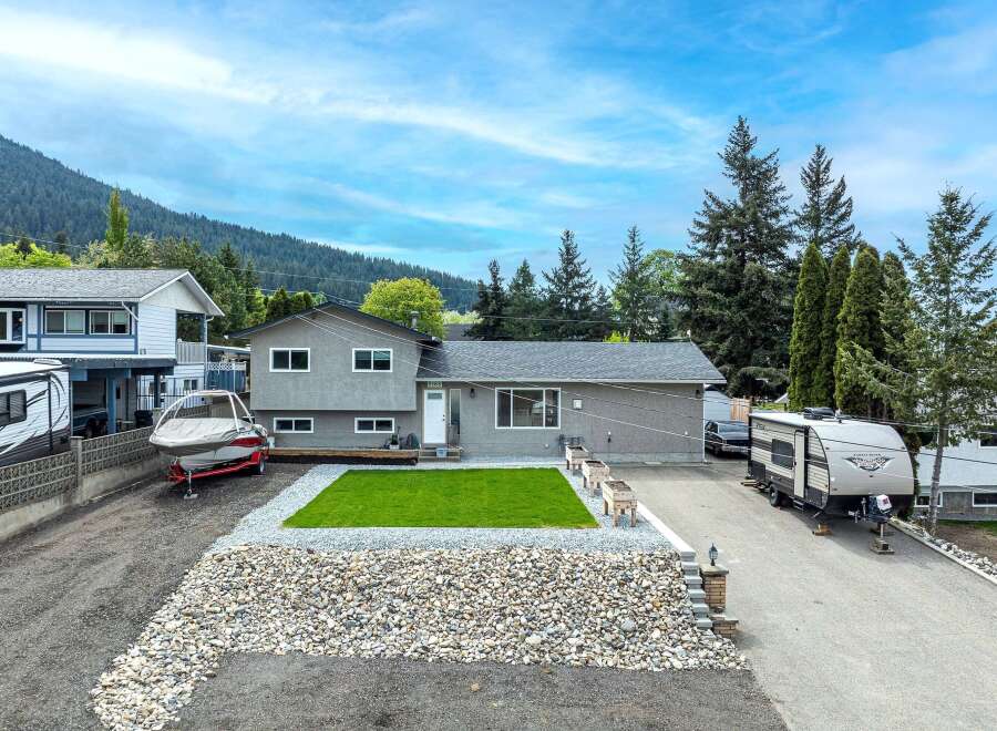 This stunning property boasts a beautifully landscaped yard with a lush green lawn and a rock garden.