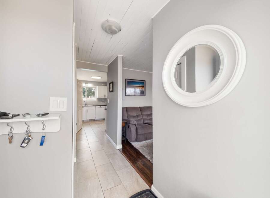 Step into this inviting entryway, showcasing a stylish round mirror and a convenient key holder.