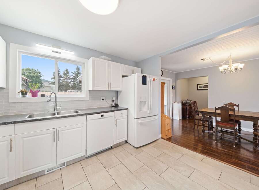 This bright and airy kitchen features white cabinetry, a modern stainless steel sink, and a convenient dishwasher.