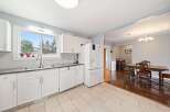 This bright and airy kitchen features white cabinetry, a modern stainless steel sink, and a convenient dishwasher.