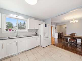This bright and airy kitchen features white cabinetry, a modern stainless steel sink, and a convenient dishwasher.