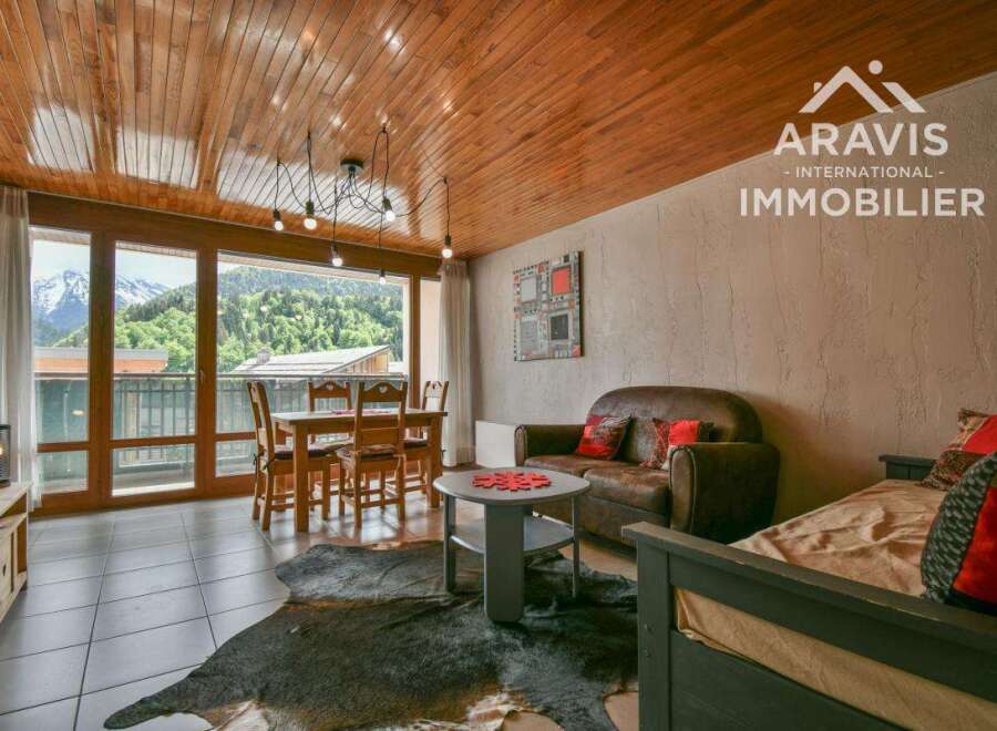 Experience the charm of this stunning property, featuring a cozy living space with a rustic wooden ceiling and large windows that offer breathtaking mountain views.